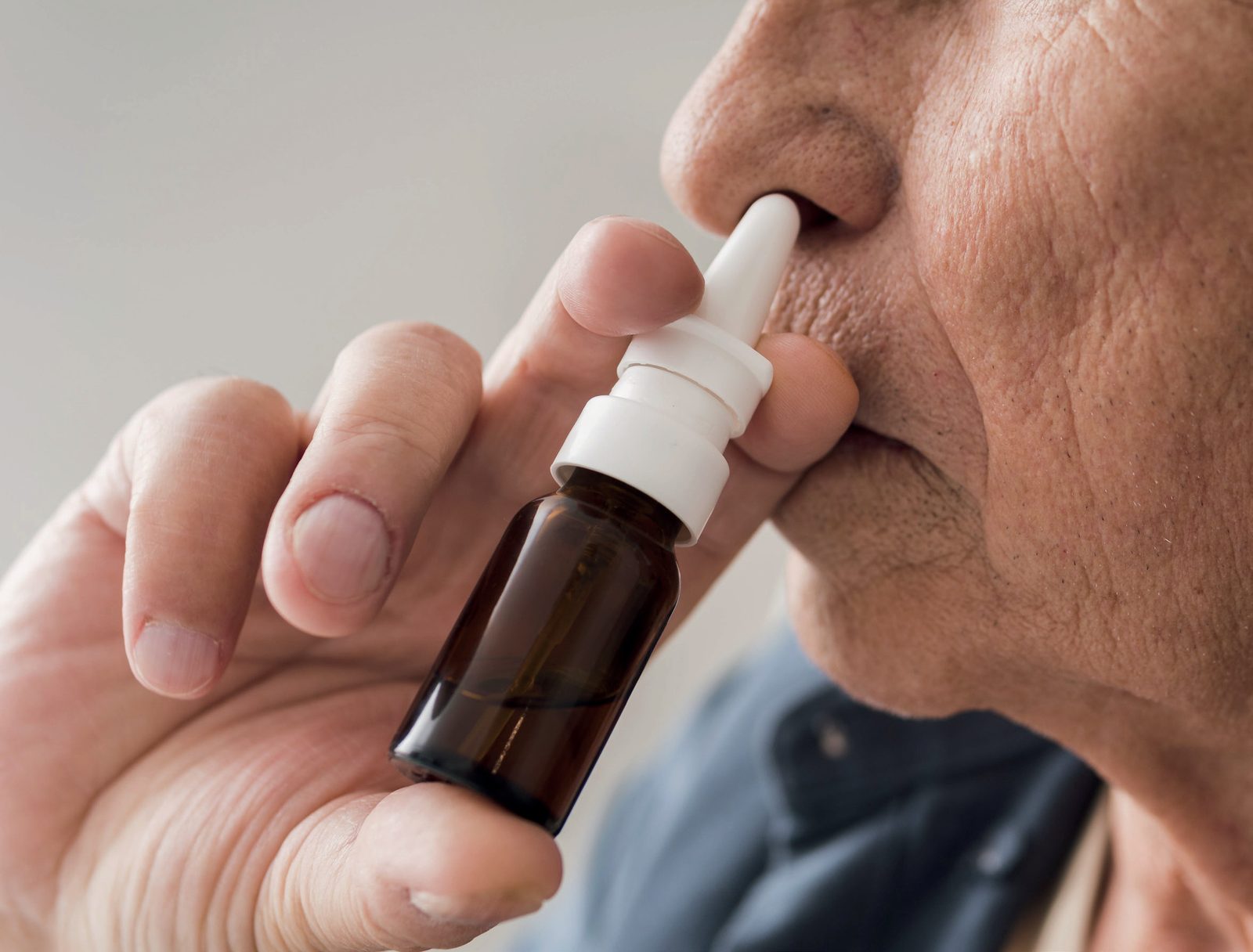 Homem idoso aplicando spray nasal