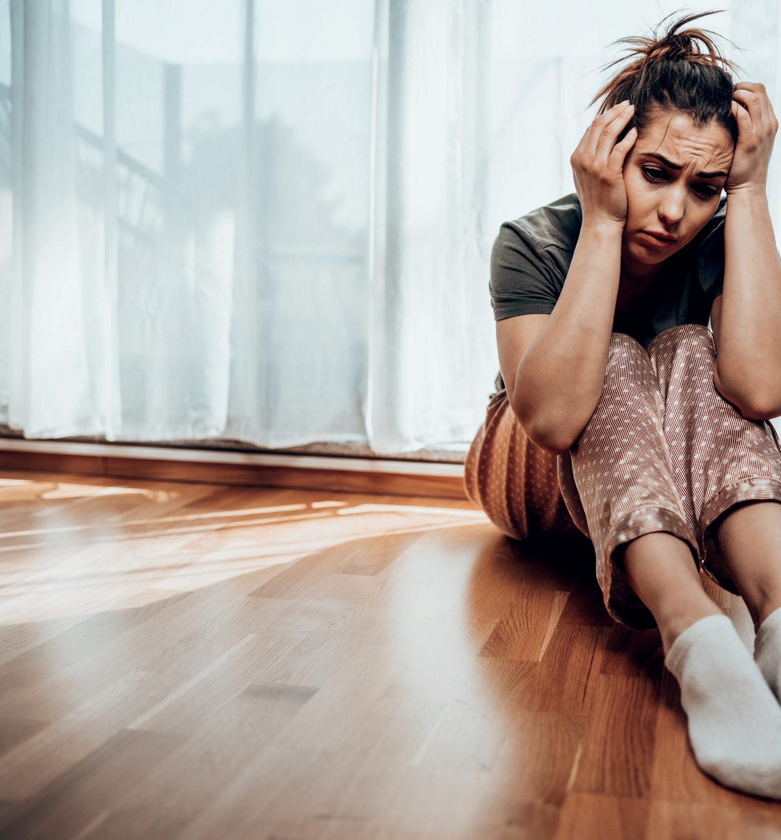 Mulher sentada com as mãos na cabeça, com expressão de cansaço mental